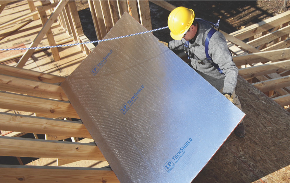 Worker placing a sheet of TechShield radiant barrier in a construction site.