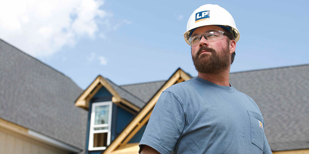 Man with LP hardhat with house in background